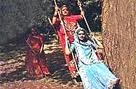 A vintage photo of a Rajasthani woman in traditional attire on a swing, with another woman in the background