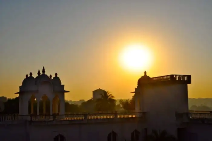 Exterior view of Savista Retreat at sunrise, featuring the silhouette of an architectural structure with domed turrets against a vibrant sun.