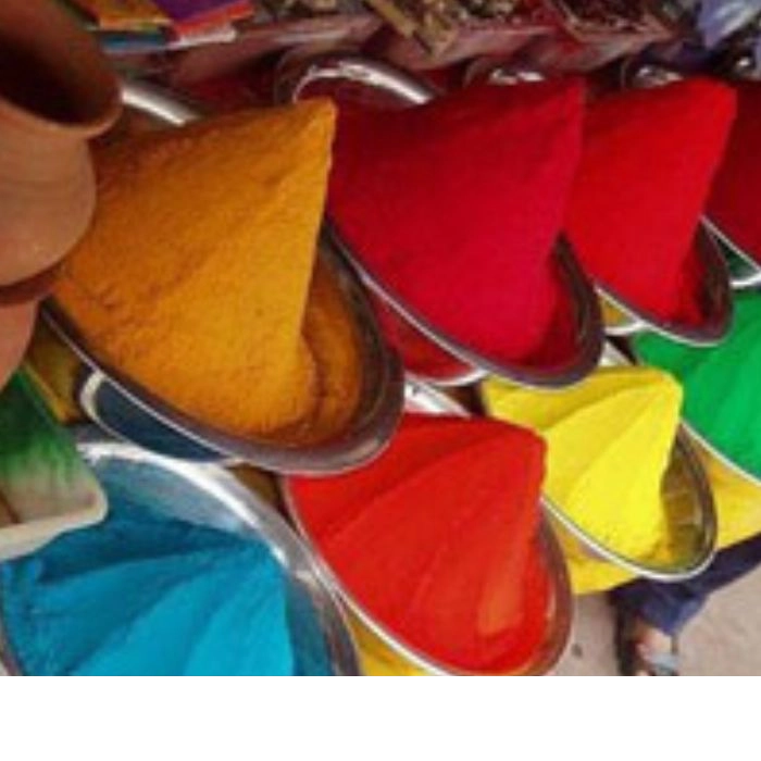 Vibrant colored powders in cone shapes stacked in metal trays, used in traditional Indian festivals like Holi and Rangoli