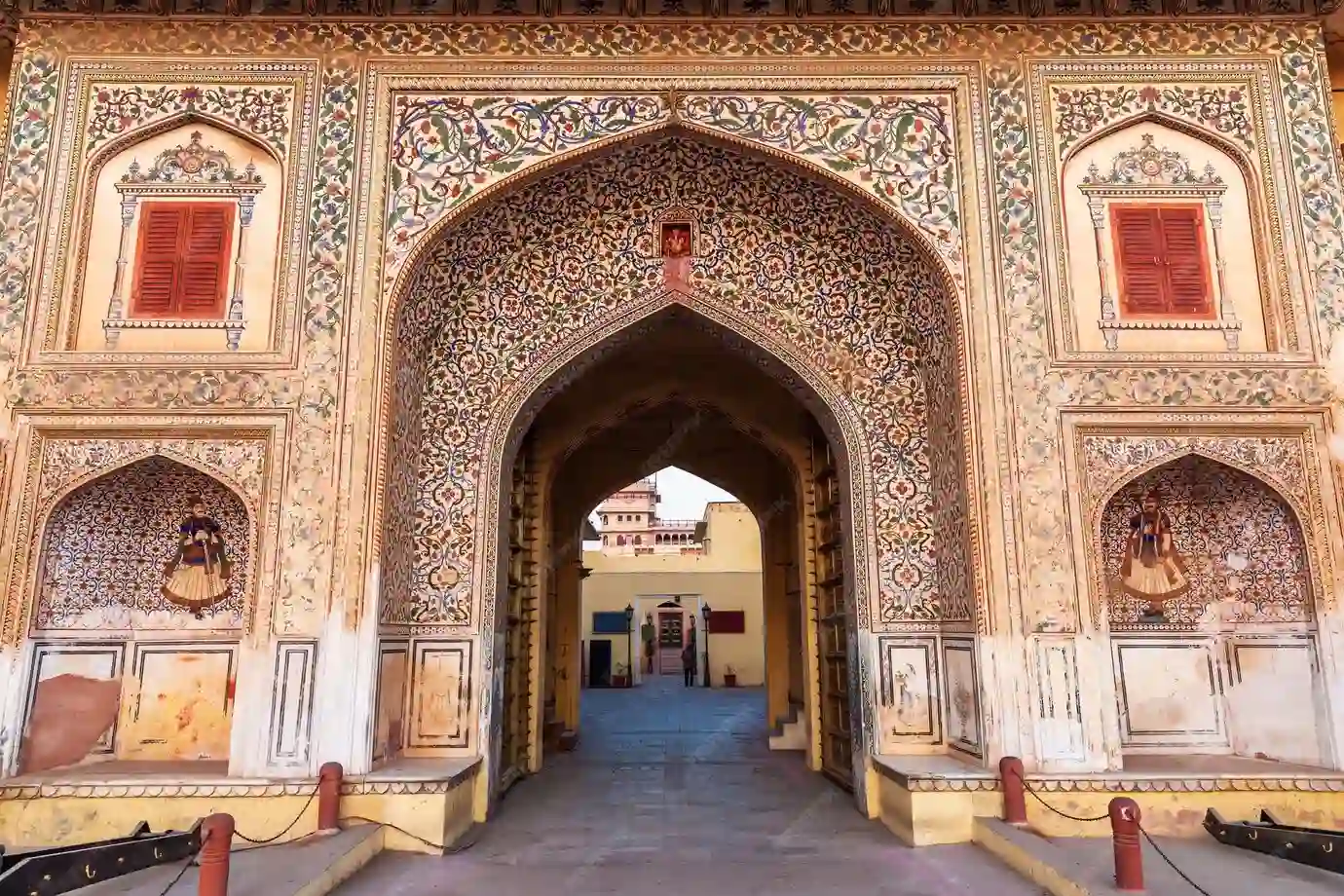 The image shows a large, ornate gateway, richly decorated with intricate floral and geometric patterns.
