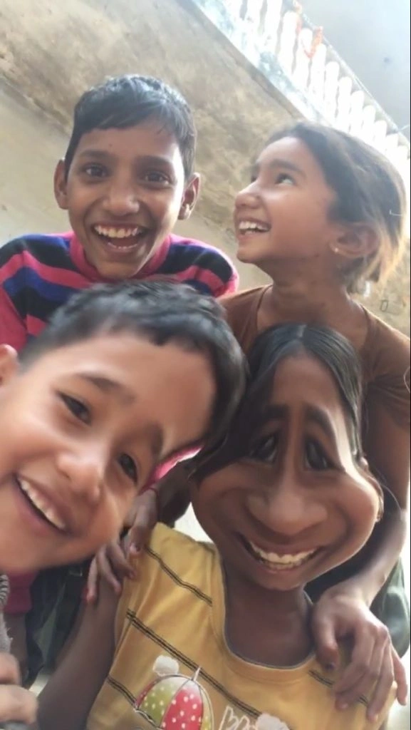 Close-up showing four smiling and lively kids. The children exhibit various emotional responses, with one looking to the right, one looking straight at the camera, the two others laughing, with their teeth on display.