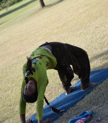 A young woman with long hair is performing the Wheel Pose, also known as Urdhva Dhanurasana, on a bright blue yoga mat.