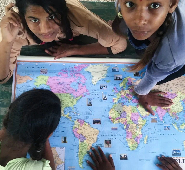 Close-up aerial shot focuses on the children around a large world map.