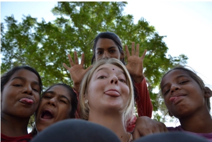 A low-angle shot shows five individuals, smiling and making playful faces.