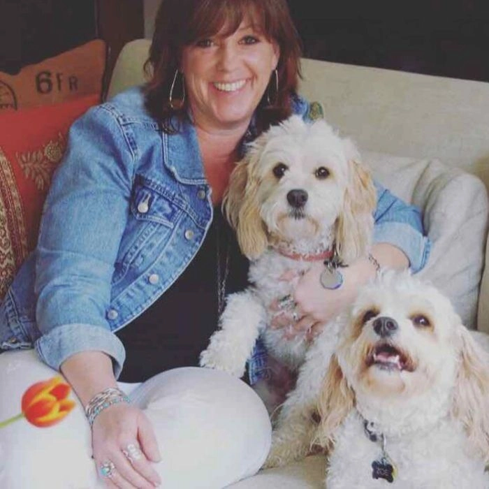The guest sitting with two fluffy dogs on a couch, enjoying a happy moment together.