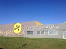 A large building with a sign that says 'Flying Fish Brewing Co.' against a bright blue sky