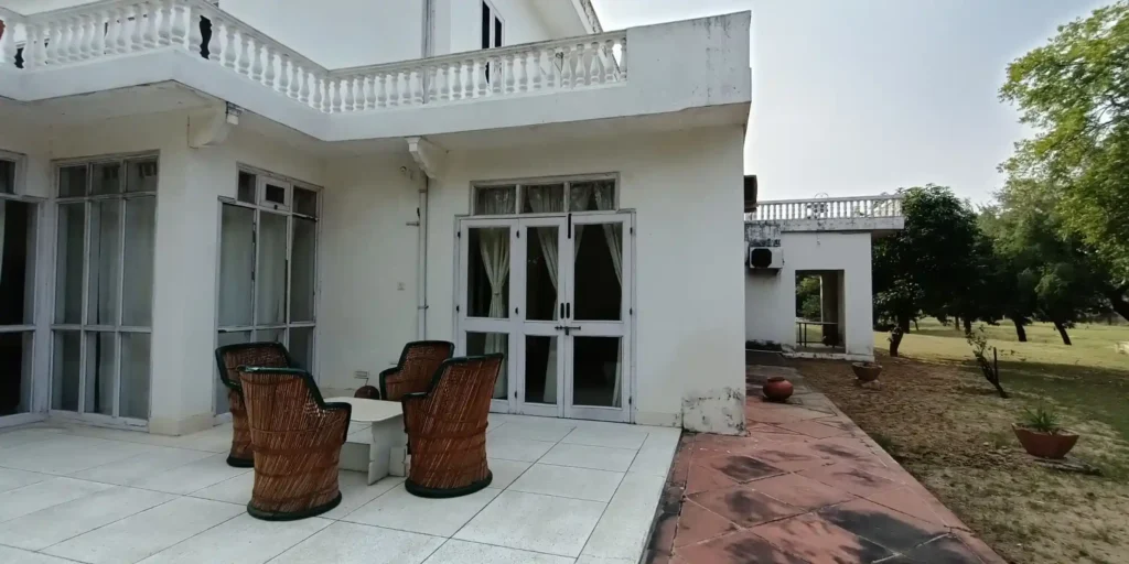An outdoor seating area with wicker chairs, a round table, and a garden view.