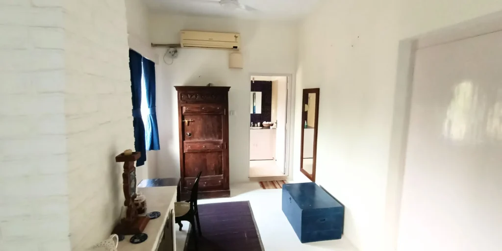 Room with vintage wooden wardrobe, small table, and simple décor.