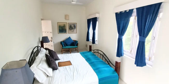 Cozy bedroom with metal bed frame, blue cushions, and natural light.