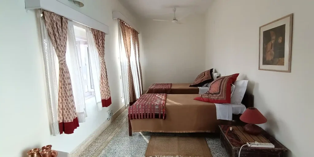 A cozy bedroom corner featuring a wooden wardrobe, a mirror, and a desk with some decorative items.