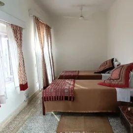 A cozy bedroom corner featuring a wooden wardrobe, a mirror, and a desk with some decorative items.