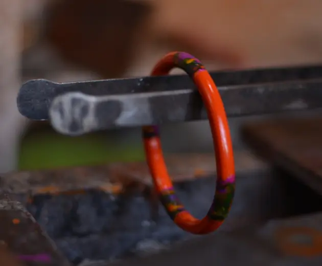 A close-up shot of a man's hands working on an bangle in a workshop, crafting with precision.