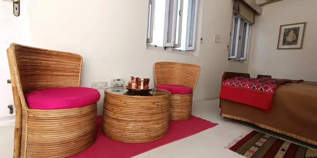 A cozy sitting area in the bedroom featuring wicker chairs with bright cushions and a glass table.
