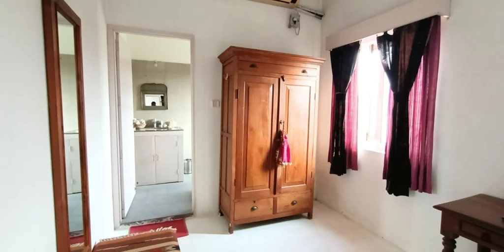 oom with wooden wardrobe, small table, and purple curtains