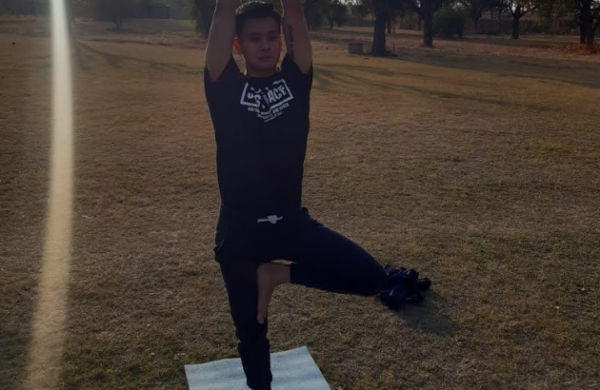 A man showing yoga pose in open space