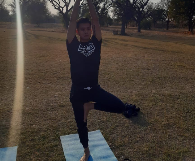 A man showing yoga pose in open space