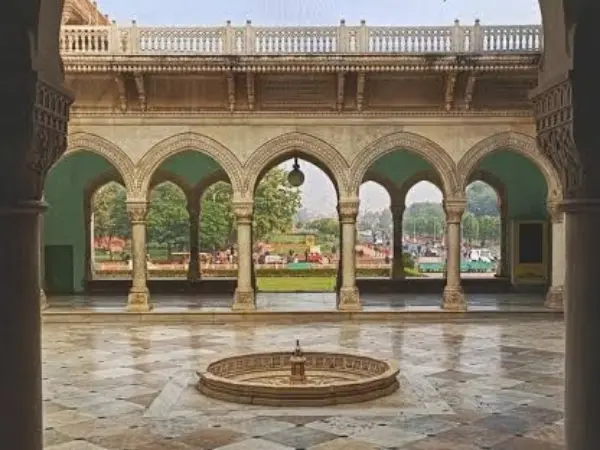 Ornate sandstone arches and a central fountain basin inside a historic Rajasthani museum courtyard.