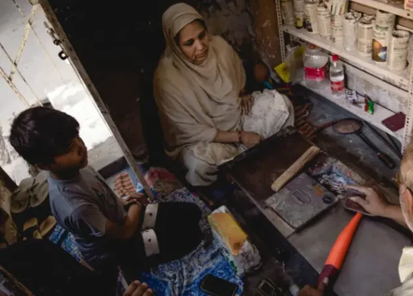 A worker carefully shaping an bangle, heating it for finishing in his crafting space.