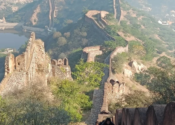 Tourists ascend the stone steps of Jaigarh Fort, with a scenic view of the fort walls and lush greenery in the background.