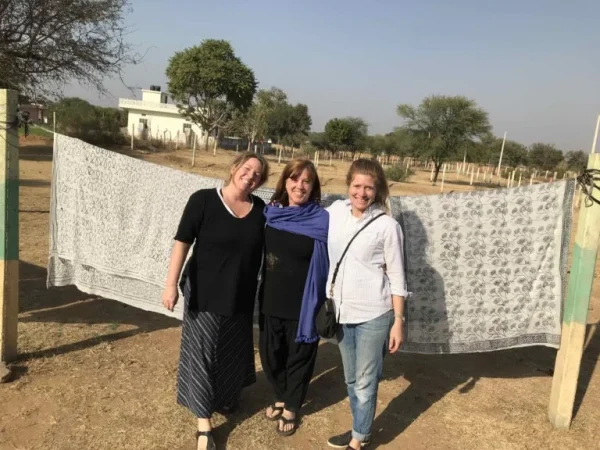 Three women standing in a rural setting with a clothesline in the background.