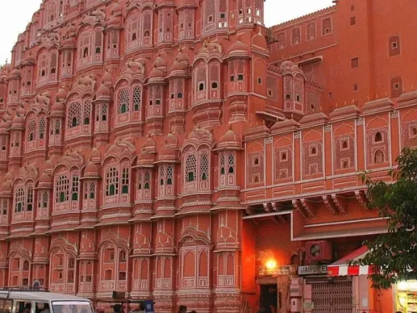 Majestic view of the Hawa Mahal in Jaipur, showcasing its intricate pink sandstone architecture with numerous windows and arches.