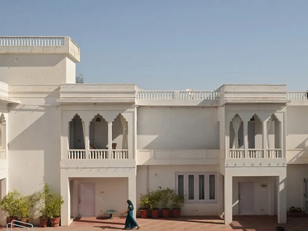A clear shot of the serene courtyard of Savista Retreat. The building is white with multiple arched balconies and walkways.