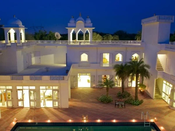 Savista Retreat, Jaipur, Rajasthan: White building lit at night with pool in foreground.