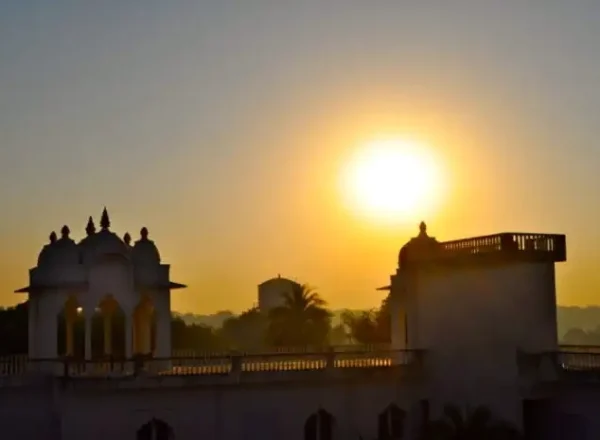 Exterior view of Savista Retreat at sunrise, featuring the silhouette of an architectural structure with domed turrets against a vibrant sun.