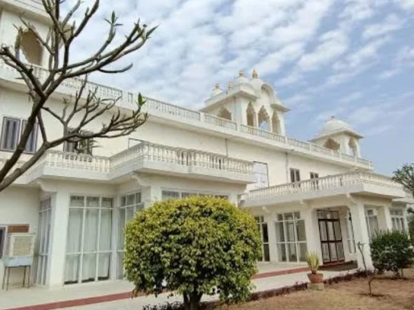 Elegant white structure with domes, ornate architecture, and a vibrant green garden beneath a bright blue daytime sky