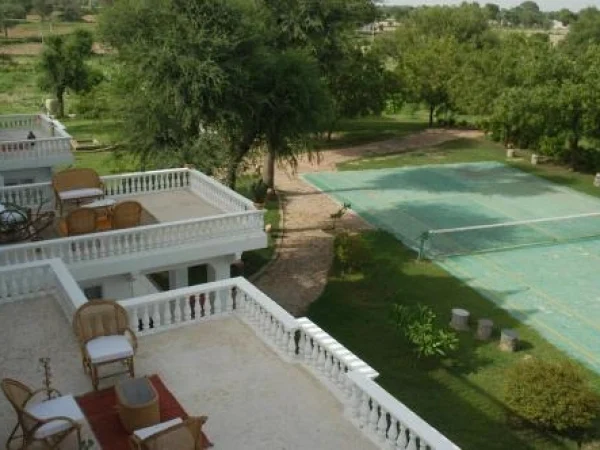 This wide, high-angle shot showcases a portion of the Savista Retreat in Jaipur, Rajasthan. Balconies overlooking tennis court and scenic Rajasthan landscape.
