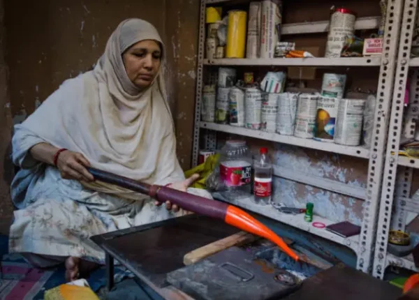 A woman making handcrafted items in a small workshop, working with colorful materials.